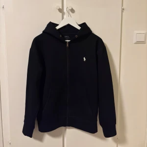 Polo Ralph Lauren zip up - Säljer en stilren svart hoodie från Polo Ralph Lauren med dragkedja och broderad logotyp på bröstet. Väldigt gott skick och använts med hänsyn
