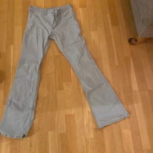 Ljusblå byxor som är low waist och boot cut - Säljer ett par ljusblå byxor från H&M med utsvängda ben och justerbar midja. Byxorna har låg midja och stängs med knapp och dragkedja. Perfekta för en avslappnad stil.
