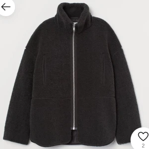 Svart teddyjacka med dragkedja - Mysig svart teddyjacka med dragkedja framtill. Jackan har en hög krage och två sidofickor, perfekt för kyliga dagar. Den har en avslappnad passform och är idealisk för både höst och vinter.