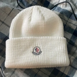 Vit ribbad mössa från Moncler - Snygg vit ribbad mössa från Moncler med broderad logotyp framtill. Perfekt för kyliga dagar och ger en stilren look. Passar både till vardags och mer uppklädda tillfällen.