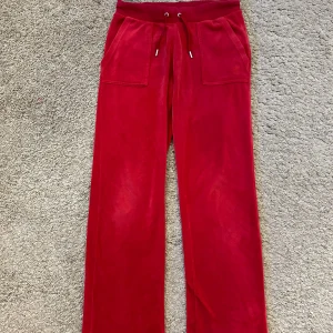 Röda mjukisbyxor från Juicy Couture - Snygga röda mjukisbyxor från Juicy Couture i en skön och mjuk velour. Perfekta för en avslappnad stil. Använt ett fåtal gånger! ❣️