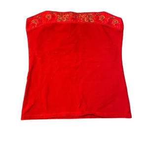 Röd tubtopp med broderade detaljer - Säljer denna röda tubtopp från indiska då den är för stor för mig. Inget synligt slitage. Avklippta band, men de märks inte. Fler bilder eller frågor? Skicka dm