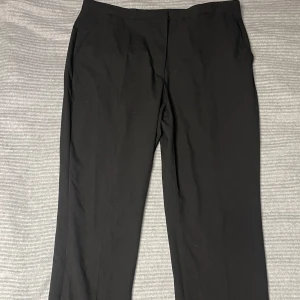 Svarta kostymbyxor från H&M - Snygga svarta kostymbyxor från H&M med en klassisk passform. Perfekta för en stilren look. Tillverkade i ett bekvämt material som passar för olika tillfällen.