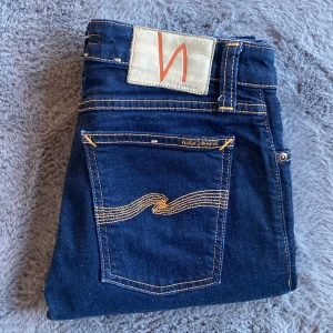 Nudie jeans W27 - Säljer ett par nudie jeans som är använda men  är som nya! Jeansen storlek W27 L32 och modellen heter skinny lin! Skriv för fler bilder eller för frågor/ funderingar!   A ≈ 81 cm B ≈ 37 cm C ≈ 43 cm D ≈ 22 cm E ≈ 15 cm F ≈ 22 cm Längd ≈ 102 cm