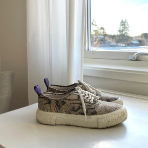 Beige sneakers med ormmönster från Eytys x H&M - Beiga sneakers med ormmönster från Eytys x H&M i storlek 38, säljer pga att de är för stora för mig!! Använda sparsamt så det är fortfarande i väldigt bra skick💞