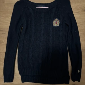 Marin blå stickad tröja från Morris - Säljer en stilren Marin blå stickad tröja från Morris med ett broderat emblem på bröstet. Tröjan har långa ärmar och ribbstickade muddar vid ärmslut och nederkant. Har aldrig använt den. Skriv vid önskemål på mer bilder eller frågor :)
