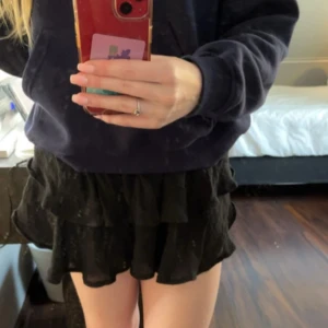 Svart volangkjol - Snygg svart kortkjol med volanger, perfekt för en trendig look. Kjolen är stretchig i midjan och luftig vilket är perfekt för sommaren. Den har inga defekter. Säljer billigt eftersom jag vill bli av med den, går ner i pris vid snabba köp!!💕