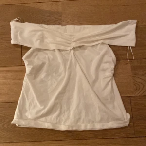 Vit offshoulder topp från Holly & Whyte - Snygg vit offshoulder topp från Holly & Whyte. Perfekt för sommarens varma dagar. Tillverkad i ett mjukt och bekvämt material som ger en stilren look.