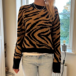 Zebramönstrad tröja i svart och beige - Snygg zebramönstrad tröja i svart och beige med långa ärmar. Perfekt för att sticka ut i mängden med ett djärvt mönster. Passar bra till jeans för en avslappnad look.