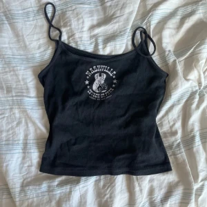 Brandy melville linne med Nashville-tryck - Snyggt svart linne med smala axelband och ett coolt Nashville-tryck på framsidan. Perfekt för en avslappnad stil.