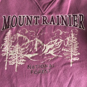 Rosa tröja ”mountrainier” - Rosa-röd tröja! (En av mina gamla favoriter) Använd, men inga fläckar eller andra skador. Lite luddig och väldigt mysig insida. Kan ta fler bilder i dagsljus om det önskas:)