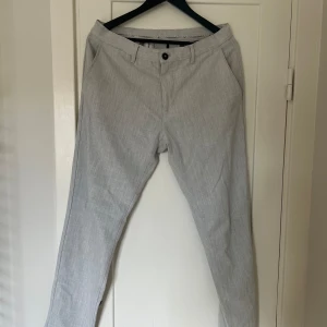 Grå byxor från Zara - Säljer ett par stilrena grå byxor från Zara i storlek EUR 42/USA 32. De är tillverkade i Turkiet och har en klassisk design med knappar och dragkedja. Perfekta för både vardag och fest!