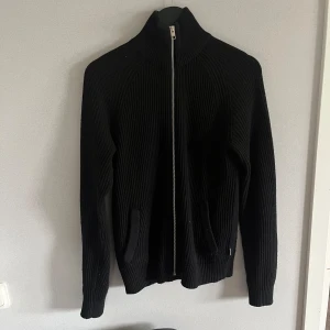 Svart ribbad kofta med dragkedja - Säljer en stilren svart stickad tröja med dragkedja/kofta. använt ett par gånger men i mycket bra skick. Taggen säger xs men skulle definitivt säga att den passar S bättre och kanske t.o.m M