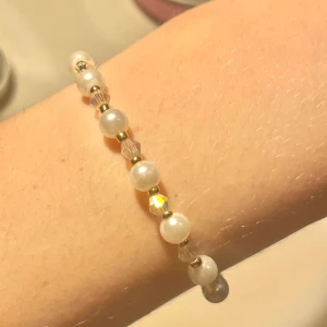 Pärlarmband  - handgjort pärlarmband med vita,guldiga och genomskinliga pärlor som skiftar i olika färger. 