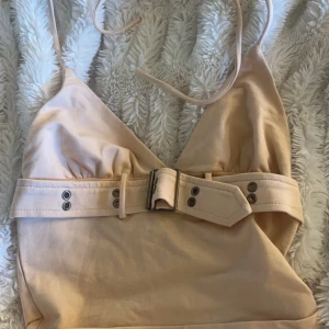 Topp - Fin ”fest” topp från edikted. Säljer den för att jag ångrade mig och det gick ej att lämna tbx😅 sitter fint med en öppen rygg och bälte detalj runt magen💕+ halter neck