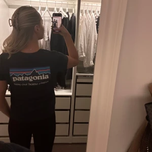 Svart t-shirt från Patagonia - Snygg svart t-shirt från Patagonia med tryck på både fram- och baksida. T-shirten har korta ärmar och en klassisk passform. Använd ett fåtal gånger så i bra skick