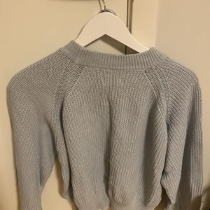Ljusgrå stickad tröja - Mysig ljusgrå stickad tröja med rund halsringning och långa ärmar. Perfekt för kyliga dagar och enkel att matcha med olika outfits.