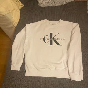Vit sweatshirt från Calvin Klein Jeans - Säljer en stilren vit sweatshirt från Calvin Klein Jeans med det ikoniska CK-logotypen tryckt på framsidan. Tröjan har långa ärmar. Perfekt för en avslappnad look. Helt oanvänd, den är äkta