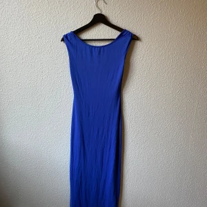Blå långklänning - Elegant blå långklänning med djup rygg. Perfekt för en stilren look.