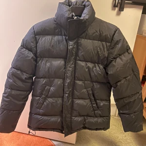Vinter jacka  - Säljer en svart pufferjacka med hög krage och dragkedja. Jackan har en quiltad design och är perfekt för kalla dagar. Den är i storlek S och har långa ärmar. Jackan köptes från Åhléns city, pris kan diskuteras!! Tveka inte att skriva!!