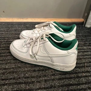 Vita Nike Air Force med gröna detaljer - Säljer ett par klassiska vita Nike Air Force med gröna detaljer. 