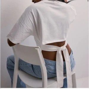 Vit kortärmad topp med knyt - Trendig vit kortärmad topp med knyt i ryggen från Nelly som är slutsåld. Säljer toppen pga att den är lite för tight på mig. Den är oanvänd men råkade dra av prislappen därav går det ej att skicka tillbaka.💗