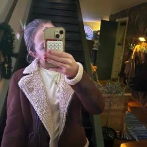 Brun jacka med teddyfoder - Säljer en snygg brun jacka med mysigt teddyfoder. Jackan har dragkedja och långa ärmar, perfekt för kyligare dagar. Den har en cool, vintage look med detaljer som ger extra stilpoäng.