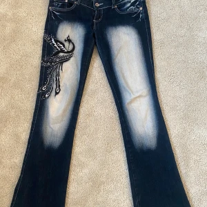 Blå jeans med broderad fågel från Crazy Age - Unika blå jeans från Crazy age. Storlek S. Midjemått: 38cm rakt över innerbenslängd: 80cm🩶 Pris kan diskuteras.