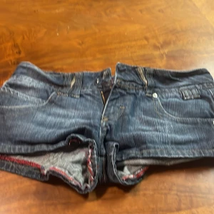 Jeansshorts från Bershka - Snygga jeansshorts från Bershka i en klassisk blå denim. De har en lågmidjad passform och är perfekta för sommardagar. Shortsen har fickor både fram och bak samt en knapp- och dragkedjestängning.