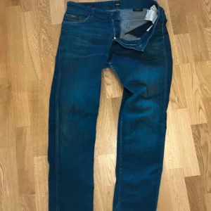 Mörkblå jeansbyxor från boss - Snygga mörkblå jeansbyxor från boss. Jeansen är i bra skick har lite använda slitningar vid vänster fikan. Storlek 33-34