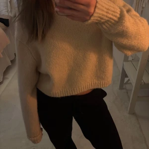 Beige stickad tröja - Säljer en mysig beige stickad tröja med croppad passform. Tröjan har långa ärmar och ribbade muddar vid ärmslut och nederkant. Perfekt för en avslappnad stil.