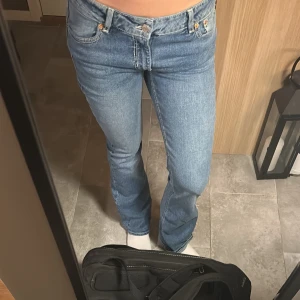 Blå bootcut jeans - Snygga blå bootcut jeans med klassisk femficksdesign och knappgylf. Perfekta för en avslappnad stil.
