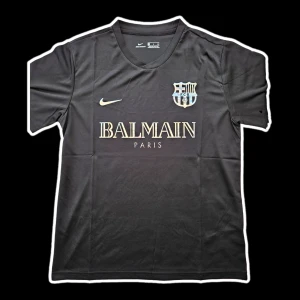 Svart fotbollströja från Nike x Balmain - Snygg svart fotbollströja från Nike i samarbete med Balmain. Tröjan har korta ärmar och ett stilrent tryck med Balmain Paris och en klubbemblem på bröstet. Perfekt för fotbollsfans som vill ha något unikt och trendigt.