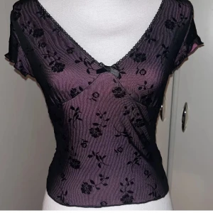 Gullig top - Gullig topp med blommigt mönster och spetsdetaljer. Toppen har en v-ringad design och korta ärmar. Den är fodrad med ett rosa tyg som ger en fin kontrast.