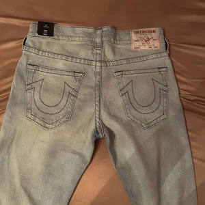 Ljusblå skinny jeans från True Religion - Säljer ett par ljusblå skinny jeans från True Religion. De har en klassisk femficksdesign och tydliga sömmar på bakfickorna. Perfekta för en stilren look. Byxorna är helt nya med lappen kvar! Strl 32 och stretchigt material