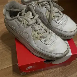 Säljer ett par klassiska Nike Air Max 90  i vitt.Skorna har en snygg och tidlös design med bekväm passform och snörning. Perfekta för både vardag och träning. De är i bra skick och kommer i originalkartong.