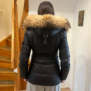 Svart hollies jacka - Det är en svart hollies jacka, med päls. Den har äkta päls. Den har två mindre hål på en av armarna och saknar dragkedja flärpar men dragkedjorna funkar bra ändå. Hålen är små och syns inte så mycket (se på bild)