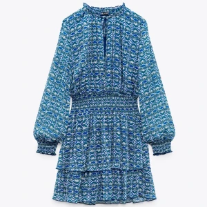 Blå mönstrad klänning - Säljer en superfin blå mönstrad klänning med långa ärmar och volangdetaljer. Kan posta på direkten!