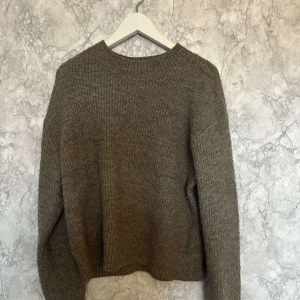 Brun stickad tröja - Mysig brun stickad tröja perfekt för kyliga dagar. Den har en enkel design med långa ärmar och en rund halsringning. Passar bra till både jeans och kjol för en avslappnad look. Perfekt för höst och vinter!