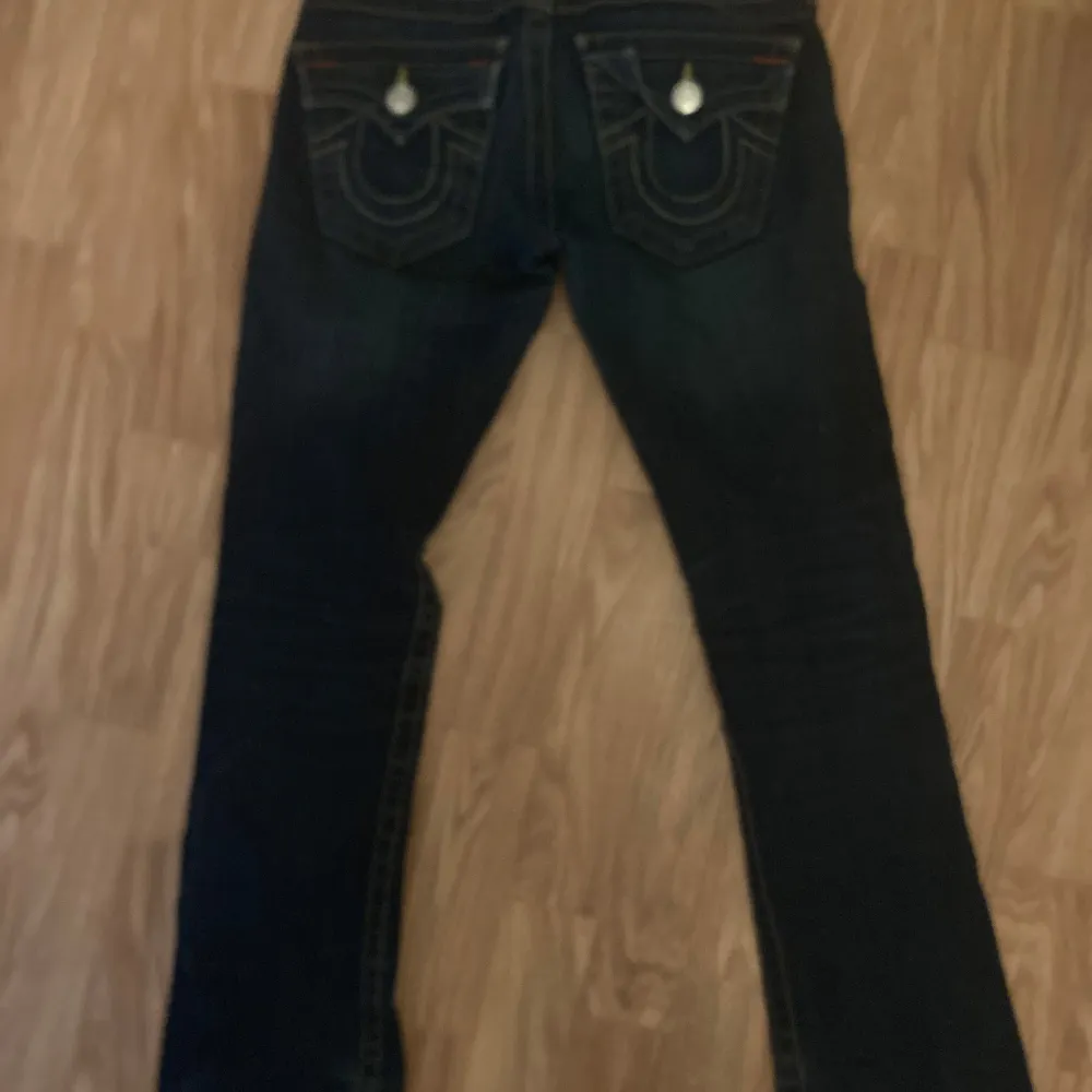 Säljer ett par snygga mörkblå jeans från True Religion i storlek 23. De har en klassisk femficksdesign med coola detaljer på bakfickorna och en knappgylf. Perfekta för både vardag och fest! 🕺Avklippta, innersöm 71 cm, yttersöm 89 cm. Midja 32cm rakt över. Mycket fint skick!. Farkut & Housut.