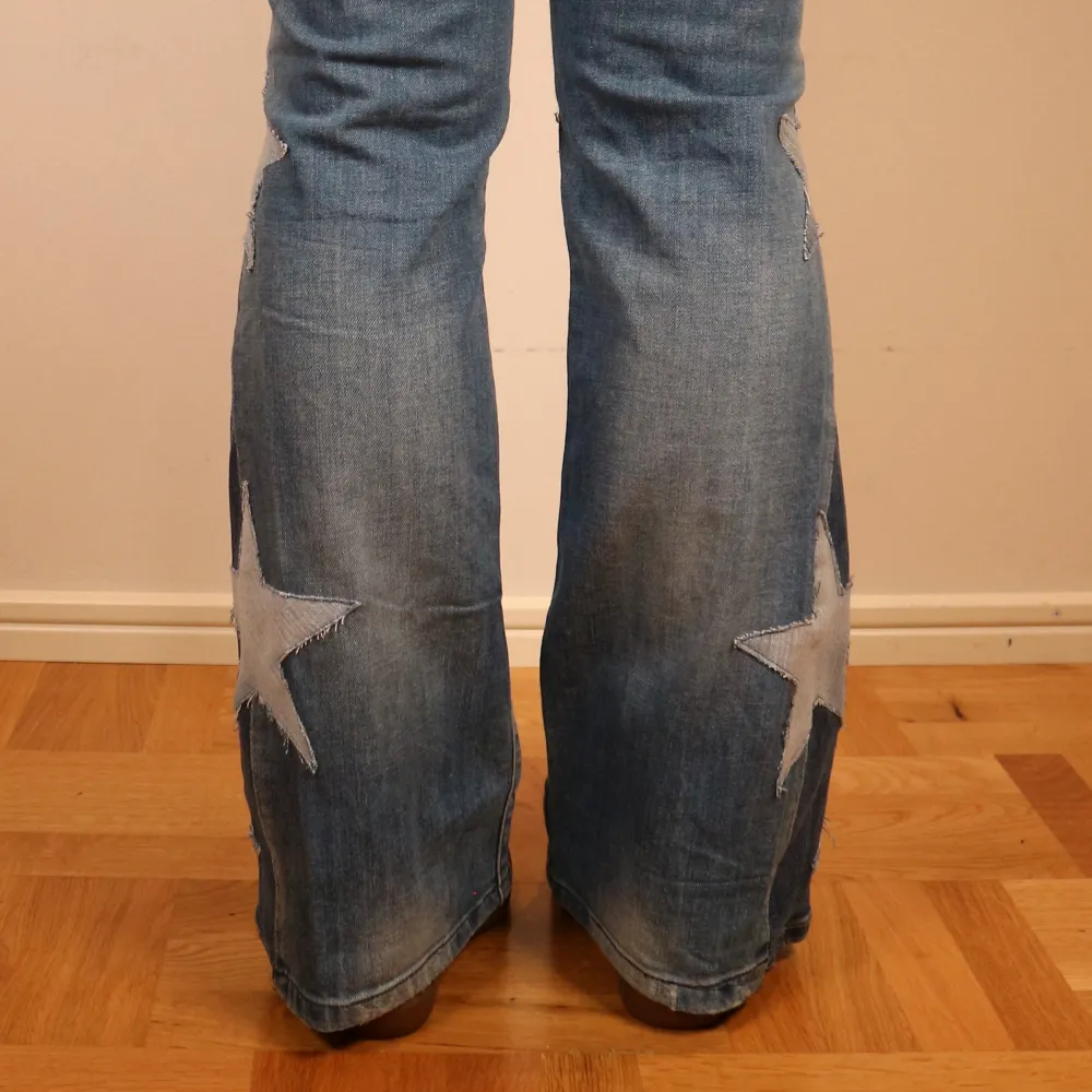 Säljer ett par coola blå jeans från G-Star RAW med unika stjärndetaljer längs benen. De är utsydda från skinny till bootcut och har en reva på ena knät. Jeansen är i bra skick och har en snygg tvättad look. Måtten är: Midja 40cm, Inneben 74cm, Ytterben 96cm. Jeans & Byxor.