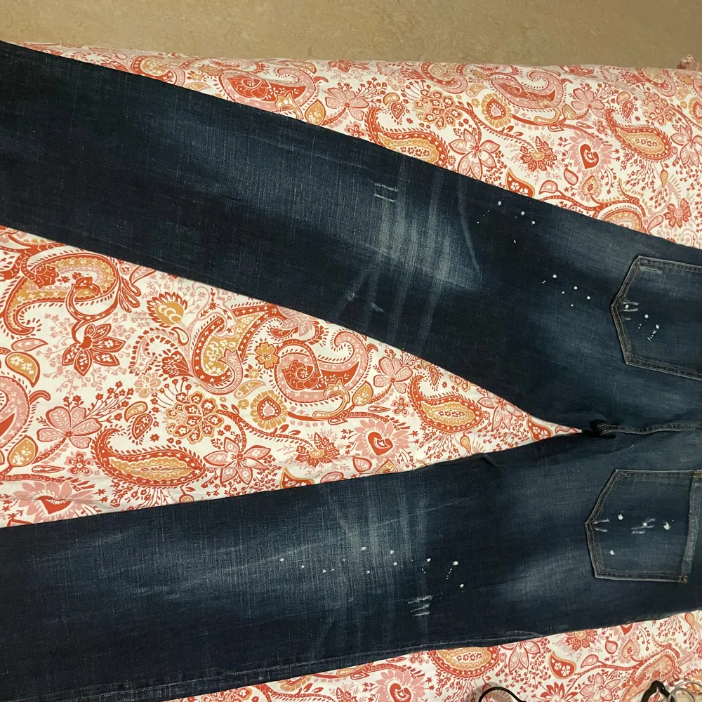 Säljer ett par mörkblå jeans från Desigual i storlek 52. De har en cool slitning och färgstänk för en unik look. Perfekta för en avslappnad stil med en touch av edge. Passar bra till både vardag och fest!. Jeans & Byxor.