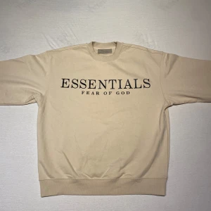 Beige Essentials Fear of God tröja - Säljer en snygg beige tröja från Essentials Fear of God. Aldrig använt den därför är den i mycket bra skick och passar perfekt för både höst, vinter och vår. OBS: Är storlek M men passar som L