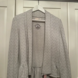 Grå mönstrad jacka från Odd Molly - Säljer en superfin grå jacka från Odd Molly. Koftan är i bra skick och har en snygg volangdetalj vid nederkanten. Storlek 1