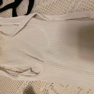 Ribbstickad vit topp zara - Ribbstickad vit topp från zara med öppen rygg samt knytning i nacken, aldrig använd men utan etikett