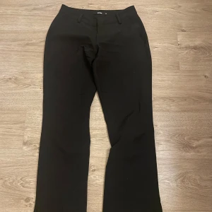 Kostymbyxor - Svarta lågmidjade kostymbyxor från bikbok med en slits längst ner i benet. Dom är bootcut.