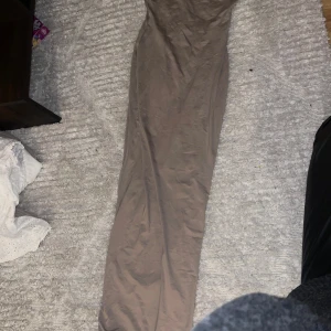 Beige byxdress från Bershka - Säljer en snygg beige byxdress från Bershka i storlek XS. Den har smala axelband och är perfekt för både vardag och fest. Materialet är mjukt och bekvämt, vilket gör den idealisk för sommarens varma dagar. Passar perfekt med ett par sneakers eller klackar för en mer uppklädd look.