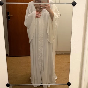 Vit långklänning med vida ärmar - Elegant vit långklänning med vida ärmar och plisserad design. Använd endast en gång på min student. Ayah abaya från Classybyy på insta. Org pris 600kr (142cm)