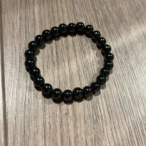 Svart pärlarmband - Snyggt svart armband med glansiga pärlor. Perfekt accessoar för att komplettera din outfit. Elastiskt band för enkel passform.