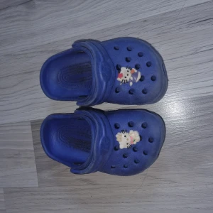 Blå sandaler/tofflor  - Säljer ett par blå sandaler/tofflor med hål och dekorationer går att plocka bort) på ovansidan. Storlek 26 men de stämmer inte alls utan dottern hade de när hon va runt 1,5 år gammal så skulle säga att de är mer som 20/21 i storlek.